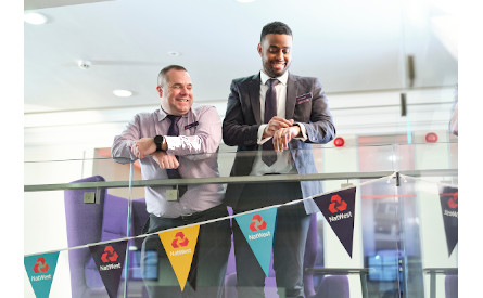 This image shows two male NatWest Group colleagues looking over a banister. 